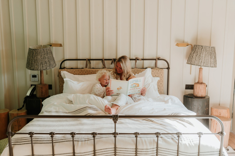 Woman and her yiung child on the bed in the treehouse at Another Place, The Lake