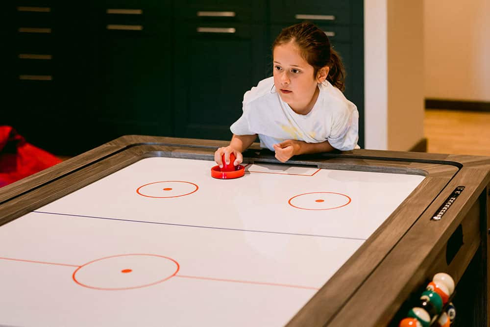 Child plays air hockey in kids zone