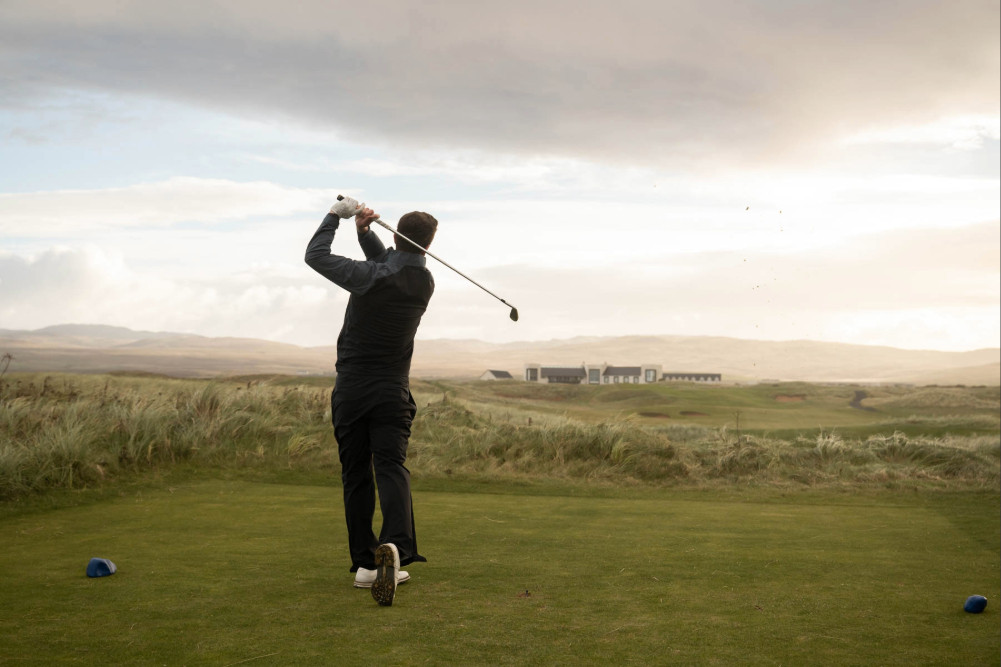 Golfer tee off at The Machrie, Islay