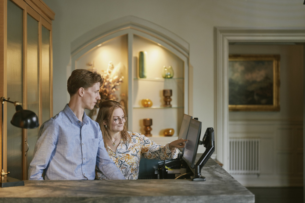 Two front desk hosts looking at a computer screen at Another Place, The Lake