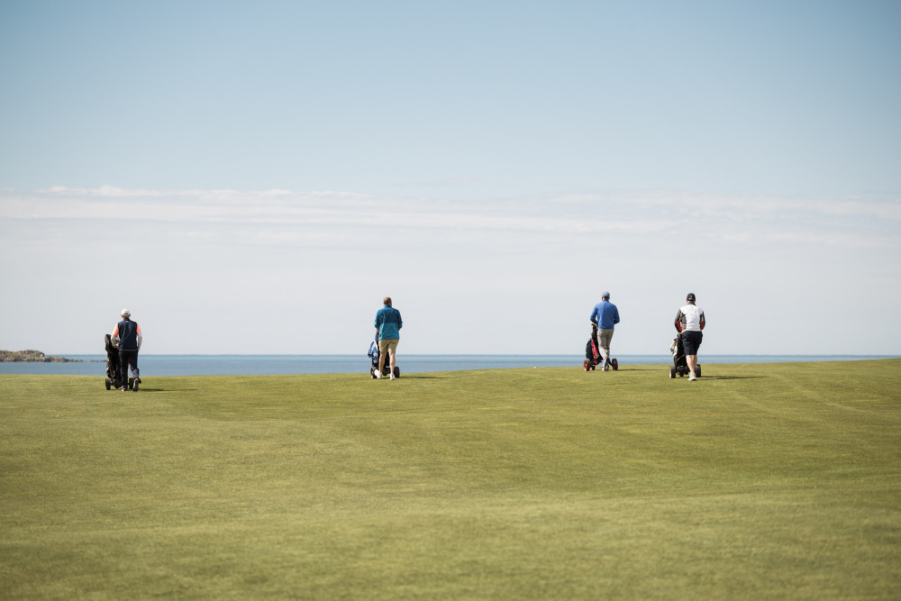 Group of people walking to the next hole on The Machrie golf course