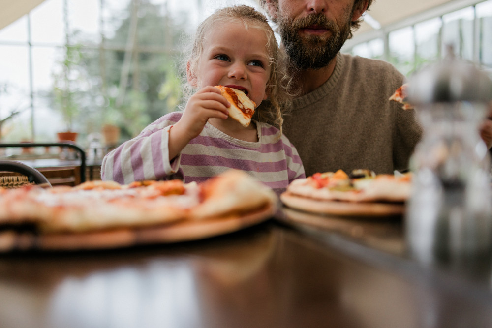 Little girl eating pizza in The Glasshouse