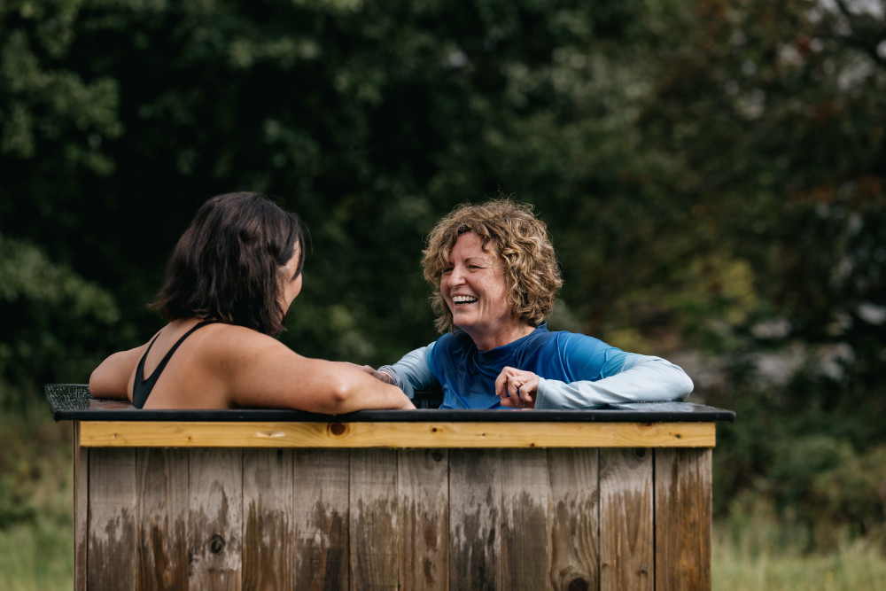 Two women in the cold plunge outside of Fellside Sauna at Another Place, The Lake in Ullswater