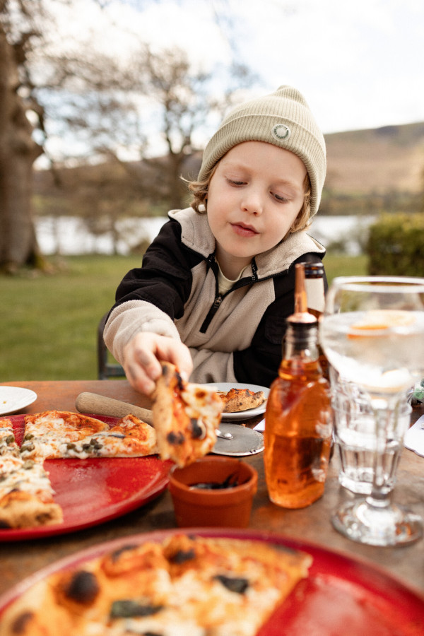 Child eating pizza from the Glasshouse at Another Place, The Lake