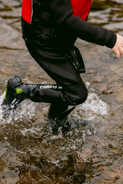 Child wearing a wetsuit and splashing around in the shallows of the lake at Another Place, The Lake