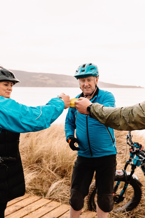 Group of people sat in the on fatbikes at Another Place The Machrie, cheersing