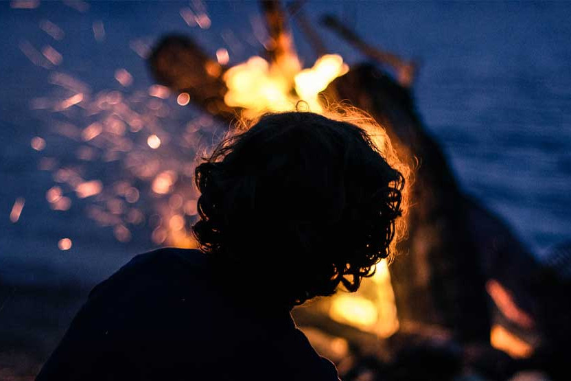 Child enjoying a lake side bonfire