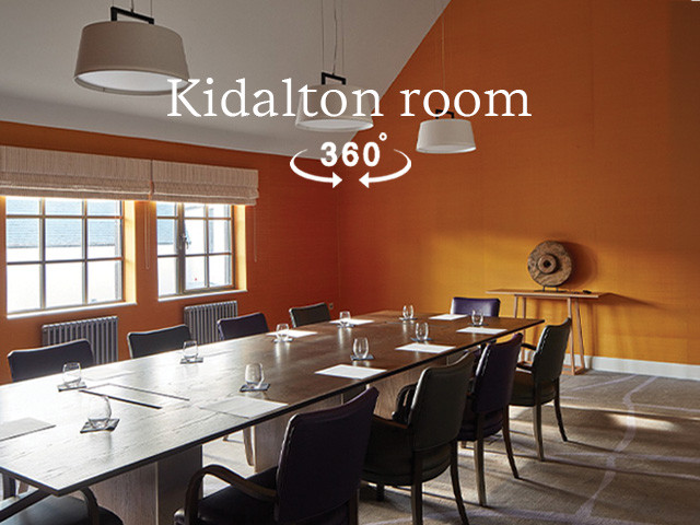 Conference room with ornage wallpaper, a large table in the centre and flip chart to the side, with a big TV screen on the far wall