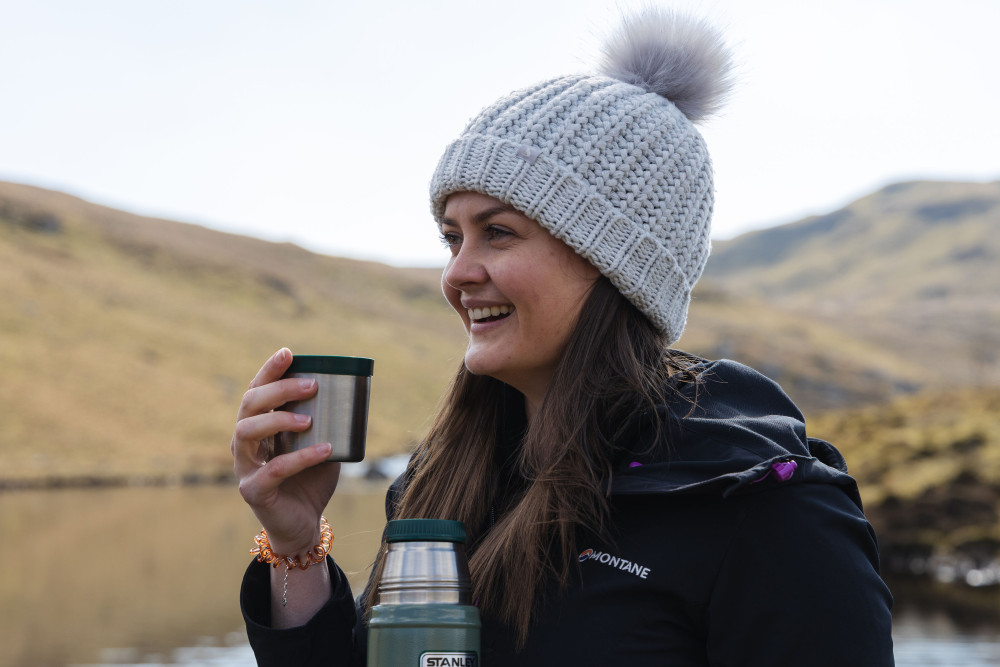 Woman holding and drinking from a stanley flask on the fells