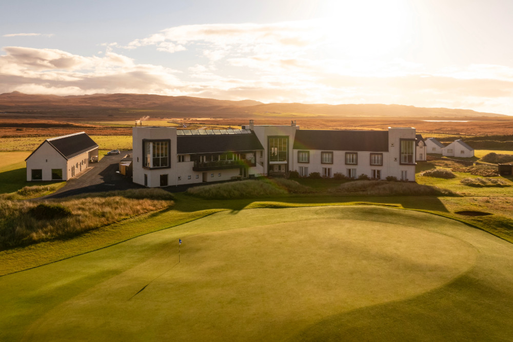 Aerial shot of the 18th hole of The Machrie, Islay golf course, with the hotel in the background at sunset