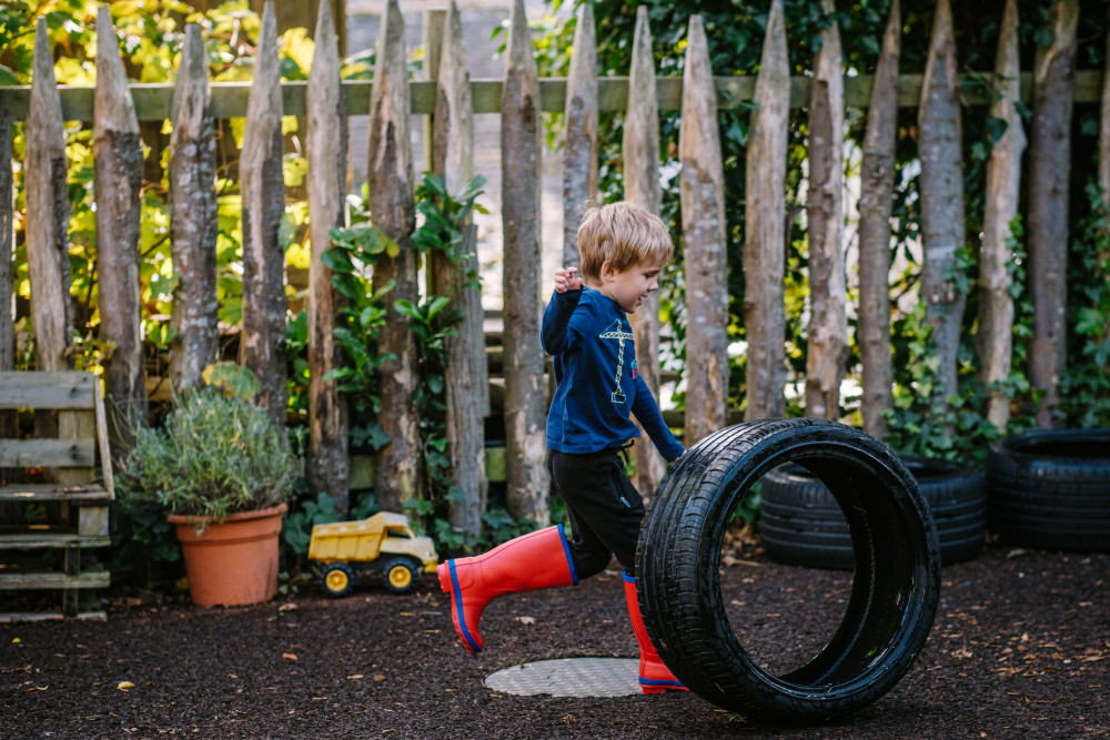 Child running with a tyre outside Kids' Zone at Another Place the Lake