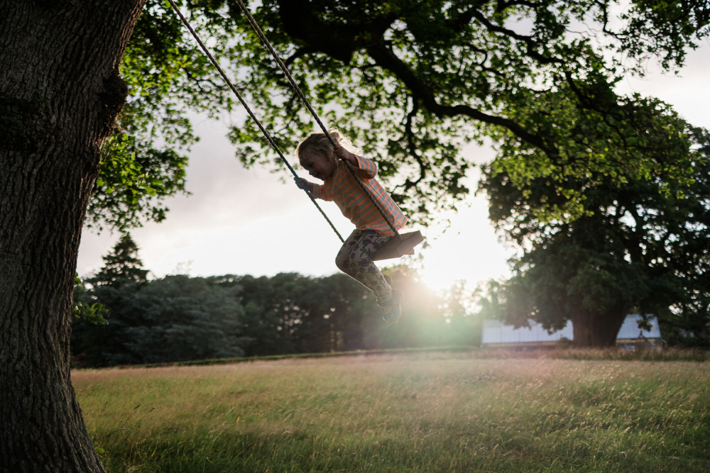 Child on the swing under the oak tree at Another Place The Lake