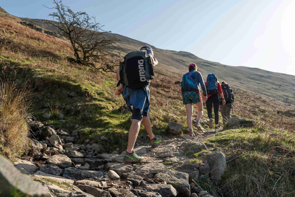People hiking up Angle Tarn with rucksacks on their backs