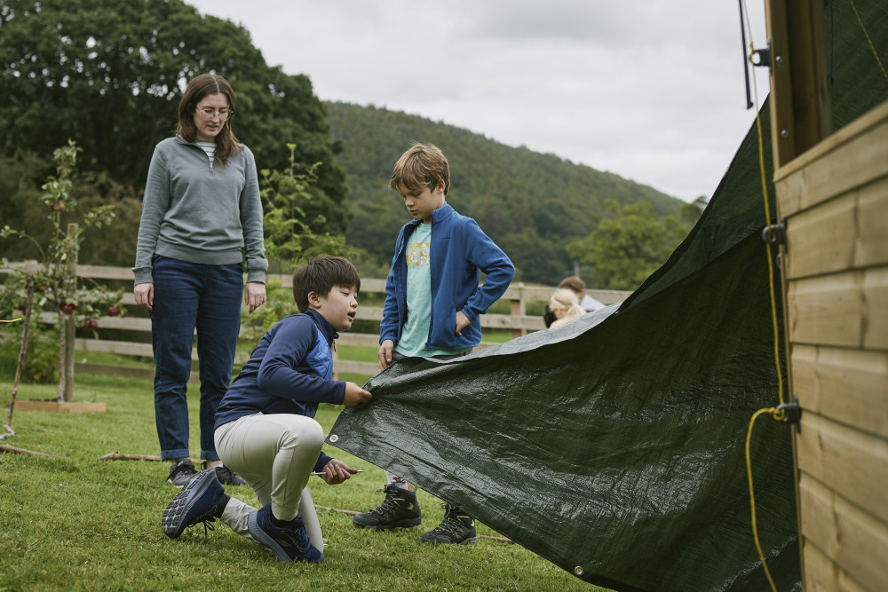 Two children building a den as part of forest school at Another Place, The Lake 