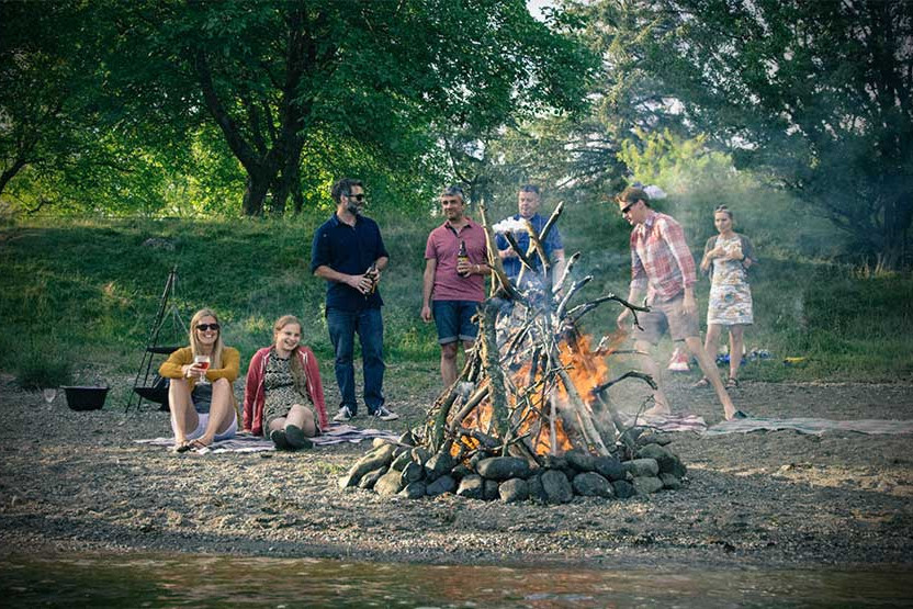 Group of people around a fire on  the lake shore